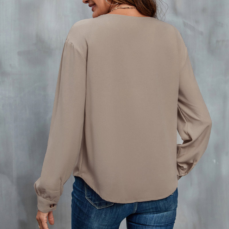 Frau in beiger Bluse und blauer Jeans von hinten, lässiger Stil, grauer Hintergrund. Mode, Damenbekleidung, Freizeitlook.