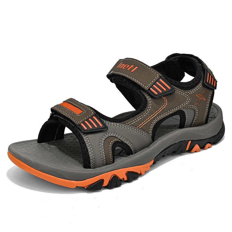 Graue und orange Outdoor-Sandale mit Klettverschluss, rutschfester Sohle und robustem Design. Ideal für Wandern und Trekking. Herrenschuh.