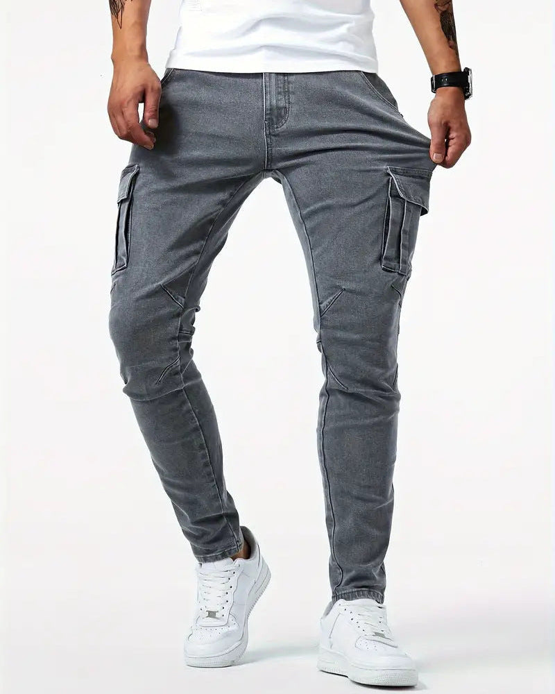 Mann trägt graue Cargo-Jogginghose mit Taschen, kombiniert mit weißen Sneakers und weißem T-Shirt. Modische Herrenbekleidung, lässiger Stil.