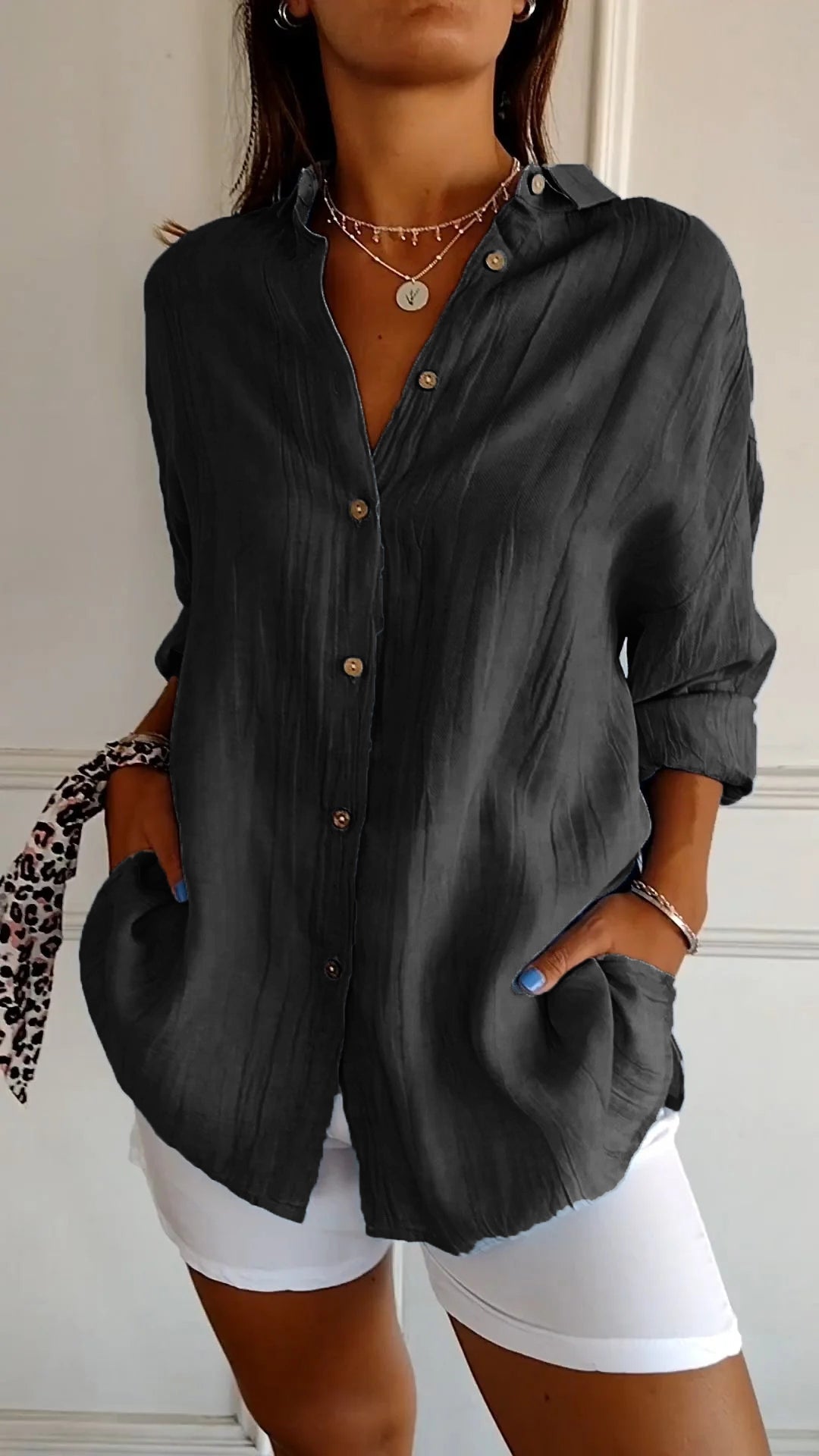 Dunkelgraue Damenbluse mit Knopfleiste, lässig geschnitten, kombiniert mit weißer Hose. Perfekt für modische Freizeitoutfits.