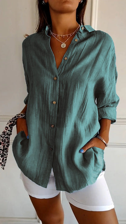 Frau in türkisfarbener Leinenbluse mit Knopfleiste und weißen Hosen, modisches Outfit, lässiger Stil, Sommermode, Accessoires, elegante Kleidung.