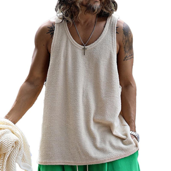 Mann mit beigem Tanktop und Kreuzkette, tätowierter Arm, hält ein Netz. Sommermode, lässiger Stil, Herrenbekleidung.
