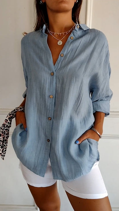 Frau in hellblauer Leinenbluse mit Knöpfen, kombiniert mit weißen Shorts. Modischer Sommerlook, lässig und stilvoll.