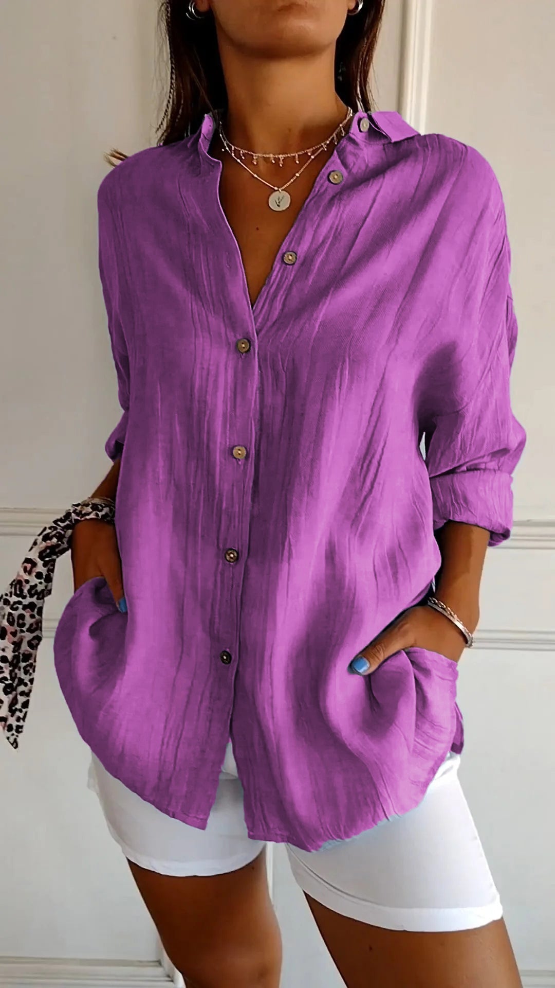 Frau trägt lila Leinenbluse mit Knopfleiste und weißen Hosen. Modischer Look, lässiger Stil, Sommeroutfit, Damenmode, trendige Kleidung.