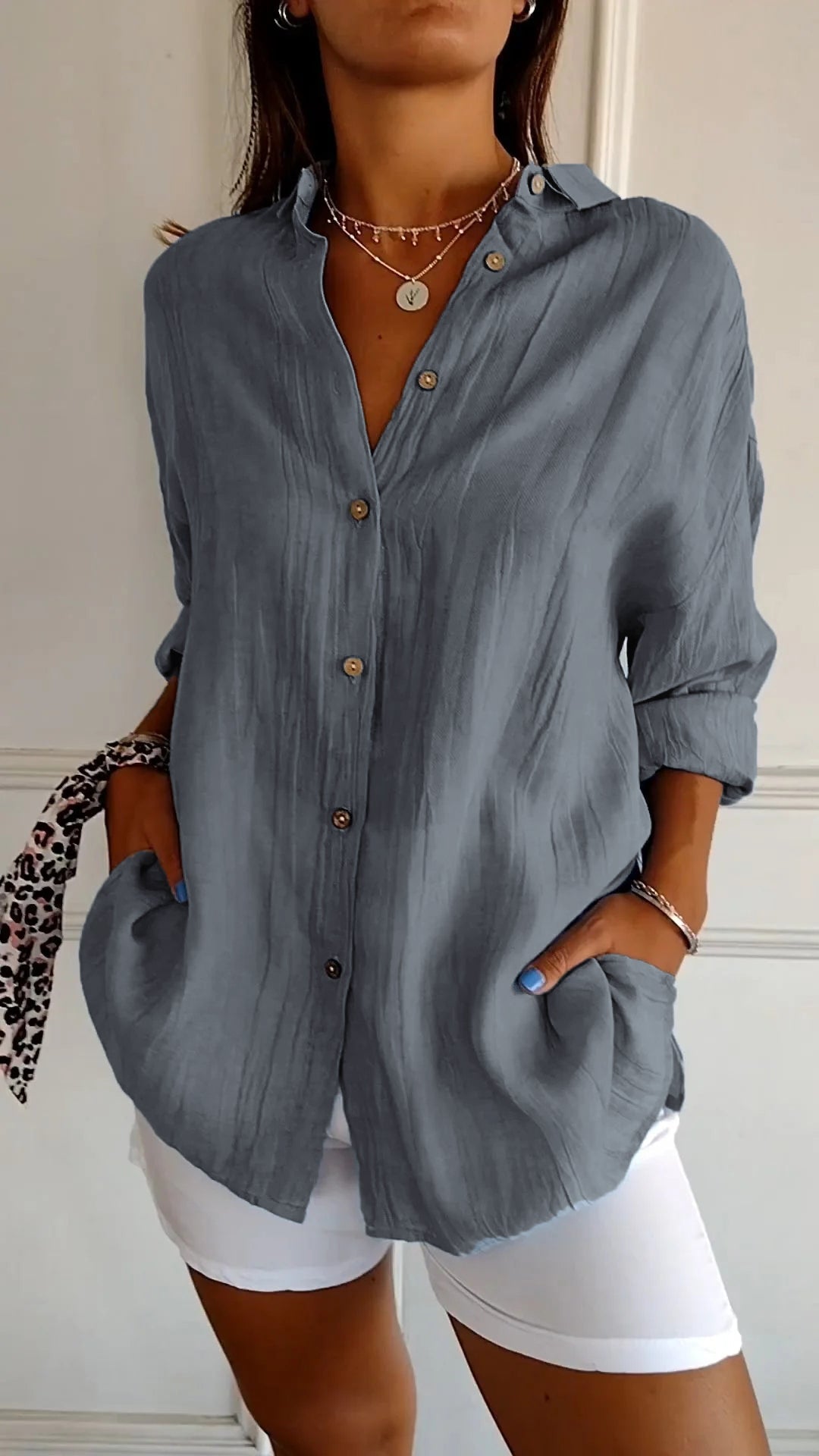 Frau in grauer Leinenbluse mit Knopfleiste und weißen Hosen, modisches Outfit, lässiger Stil, Accessoires, Sommermode, elegantes Design.