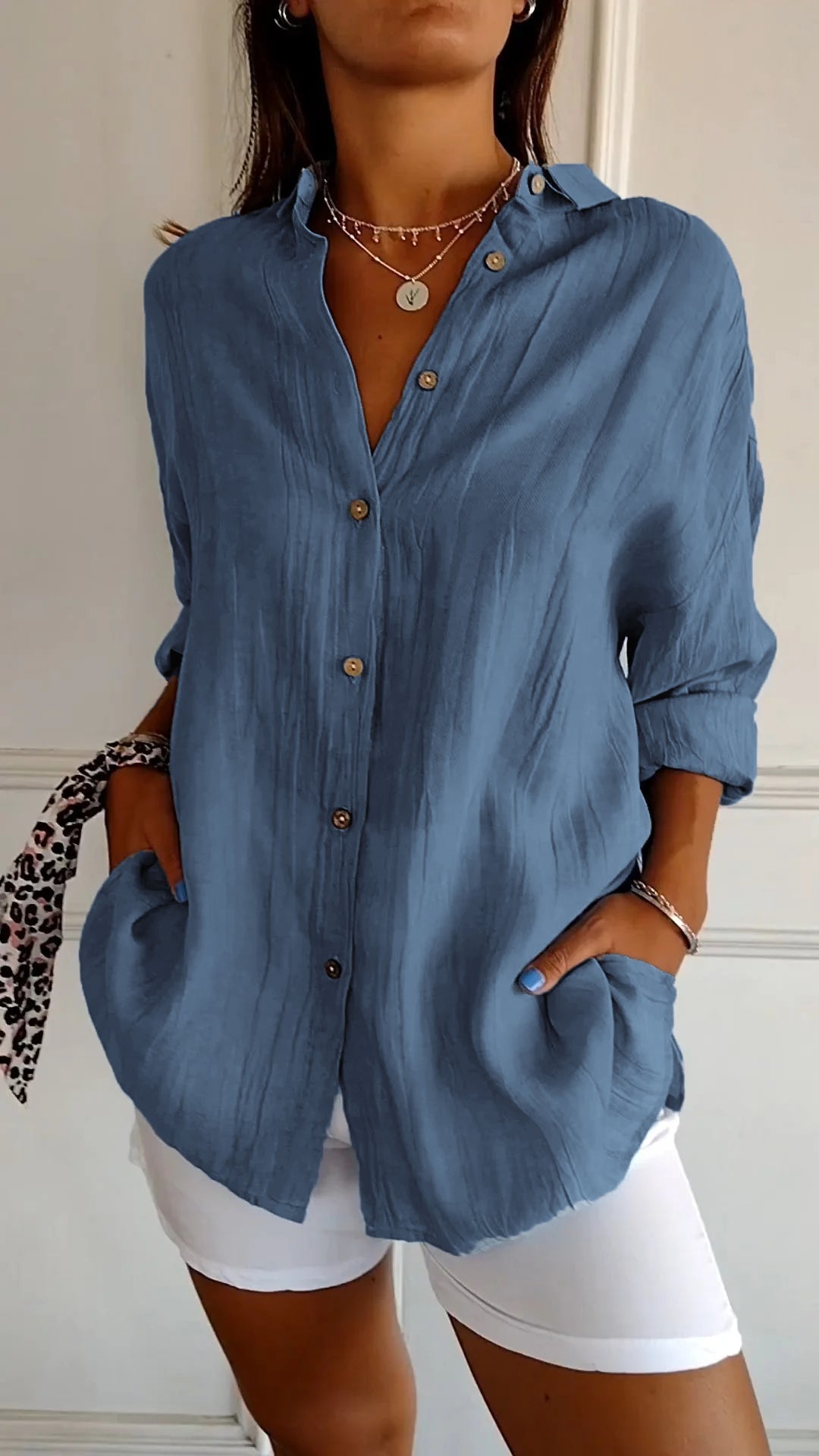 Frau in blauer Leinenbluse mit Knopfleiste und weißen Hosen, modisches Outfit, lässiger Stil, Sommermode, Accessoires, elegantes Design.