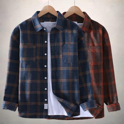 Zwei karierte Flanellhemden auf Kleiderbügeln, eines in Blau und eines in Braun, vor neutralem Hintergrund. Perfekt für Herbstmode und lässigen Stil.